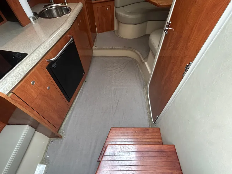 Slide: The Image of 2006 Cruisers Yachts 300 Express interior with kitchenette, seating, and wooden steps. - 42