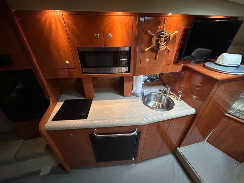 Slide: The Image of 2006 Cruisers Yachts 300 Express interior kitchen with microwave, sink, and wooden cabinetry. - 44