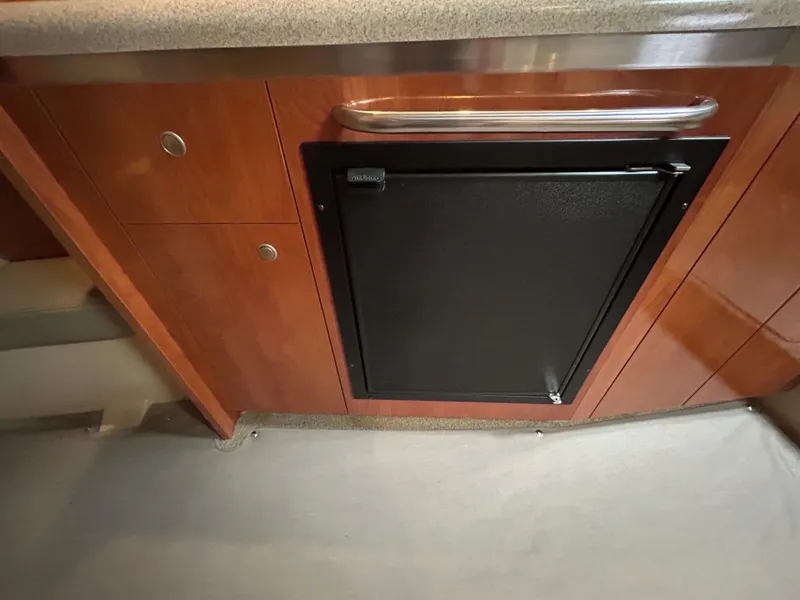 Slide: The Image of 2006 Cruisers Yachts 300 Express interior with wooden cabinetry and compact refrigerator. - 45