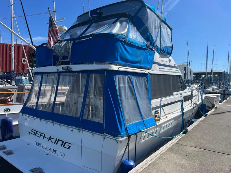 Slide: The Image of 1986 Bayliner 3870 Motoryacht docked, featuring sleek design and blue canopy under clear sky. - 1