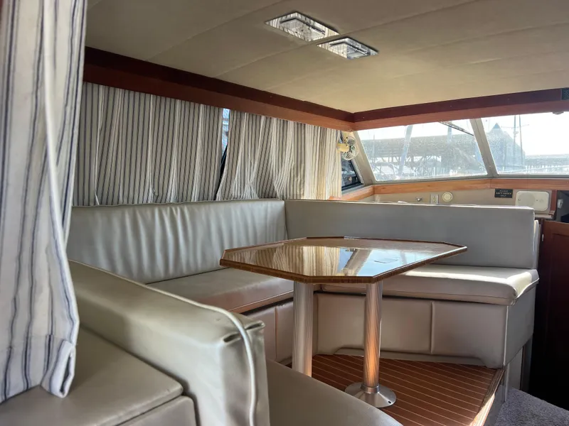 Slide: The Image of 1986 Bayliner 3870 Motoryacht interior with cushioned seating and wooden table. - 12