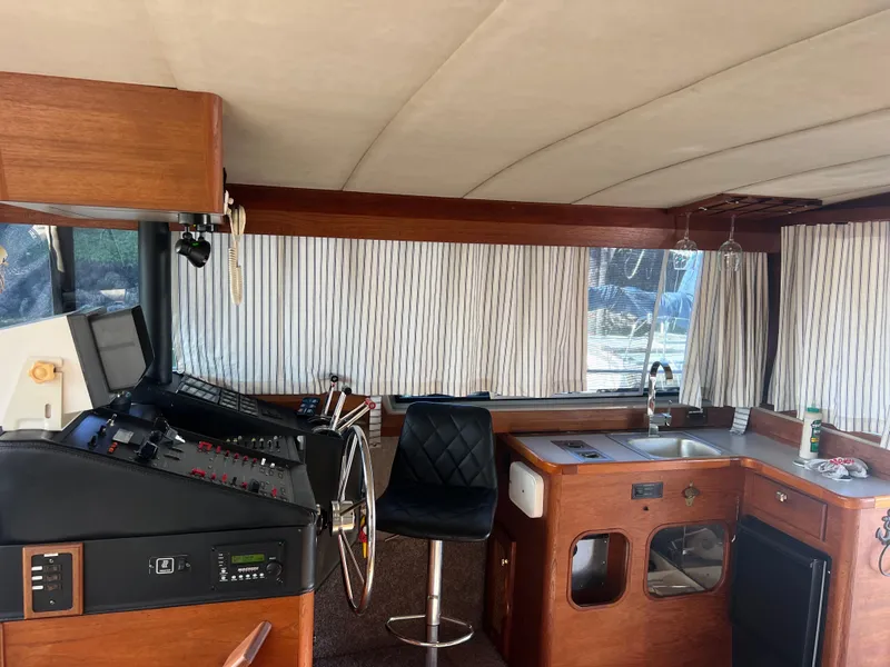 Slide: The Image of 1986 Bayliner 3870 Motoryacht interior with seating and table, featuring wood accents and curtains. - 14