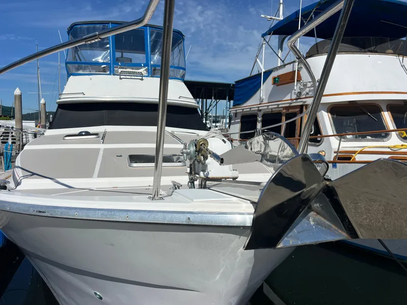 Slide: The Image of 1986 Bayliner 3870 Motoryacht docked, featuring a sleek design and blue canopy under a partly cloudy sky. - 3