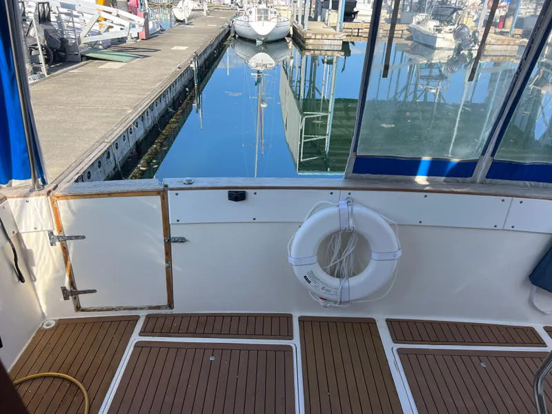 Slide: The Image of 1986 Bayliner 3870 Motoryacht helm with blue and white seating, steering wheel, and marina view. - 33