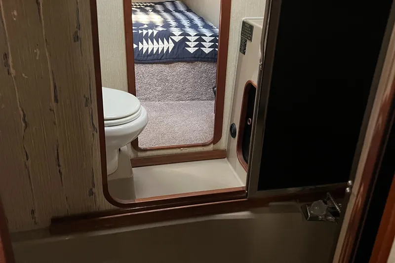Slide: The Image of Cozy cabin interior of 1986 Bayliner 3870 Motoryacht with geometric-patterned bedding. - 48