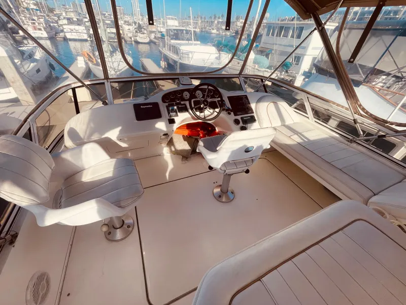 Slide: The Image of 1998 Sea Ray 370 Aft Cabin interior with beige seating, table, and windows. - 11