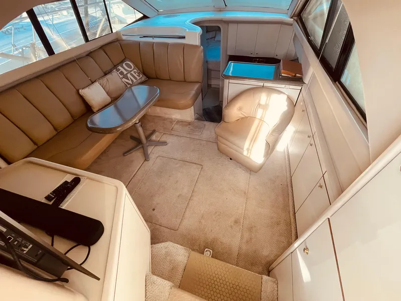 Slide: The Image of 1998 Sea Ray 370 Aft Cabin interior with beige seating, table, and TV. - 13