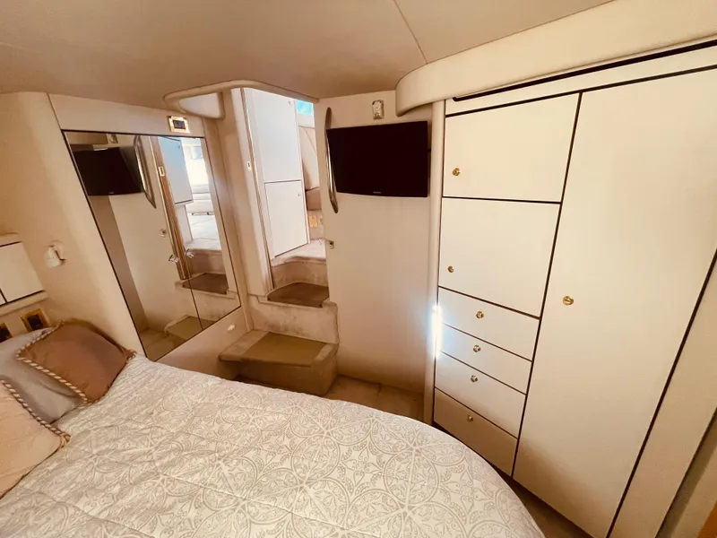 Slide: The Image of 1998 Sea Ray 370 Aft Cabin interior with bed, wardrobe, and TV. - 19