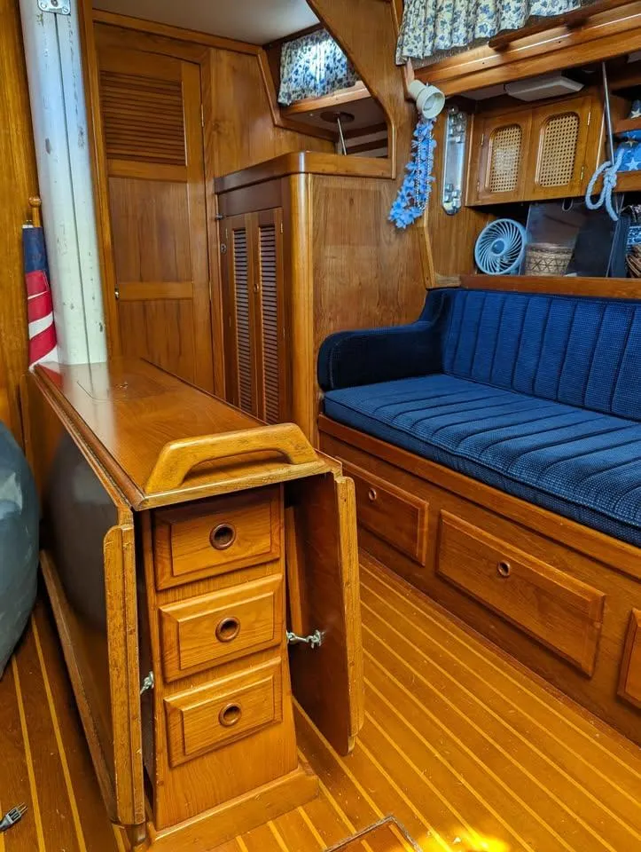 Slide: The Image of Interior of 1985 Endeavour 42 CC sailboat with wooden cabinetry and blue cushioned seating. - 10