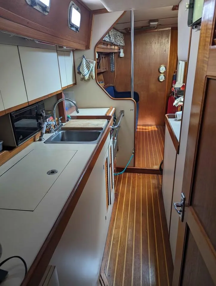 Slide: The Image of 1985 Endeavour 42 CC yacht interior with wooden flooring and compact kitchen area. - 6