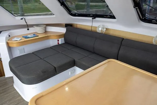 Slide: The Image of 2019 Seawind 1260 interior with gray seating and wooden table in a modern yacht cabin. - 13