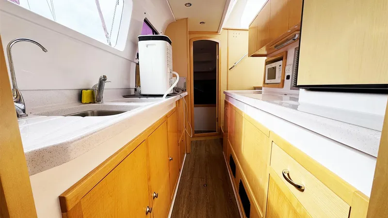 Slide: The Image of 2019 Seawind 1260 yacht kitchen with wooden cabinets, modern appliances, and sleek countertops. - 16