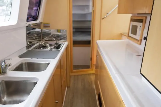 Slide: The Image of 2019 Seawind 1260 yacht interior kitchen with dual sinks and modern appliances. - 17
