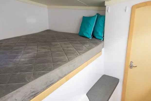 Slide: The Image of Cozy cabin interior of 2019 Seawind 1260 with bed and teal pillows. - 21