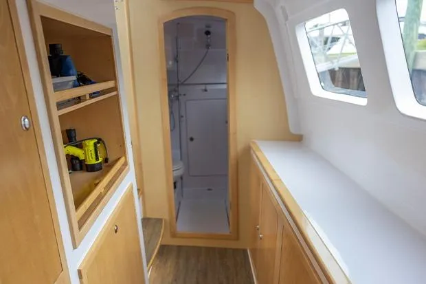 Slide: The Image of Interior of 2019 Seawind 1260 catamaran, featuring wooden cabinetry and a compact bathroom. - 27