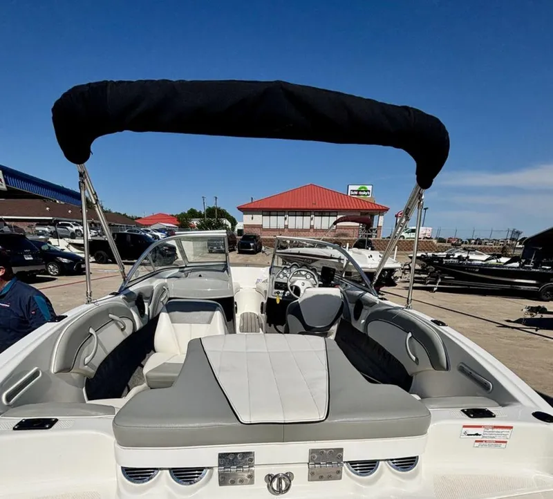 Slide: The Image of 2012 Bayliner 185 Bowrider boat with bimini top, parked outdoors under clear blue sky. - 6