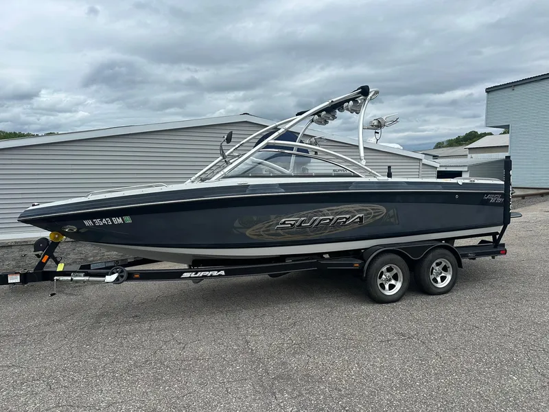 Slide: The Image of 2009 Supra Launch 22 SSV boat on trailer, parked outdoors under cloudy sky. - 1