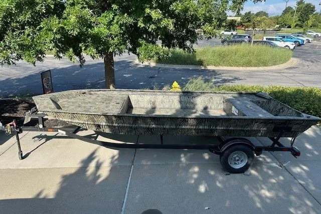 The Image of 2025 Tracker GRIZZLY 1860 Utility boat on trailer, parked outdoors under a tree. - 0