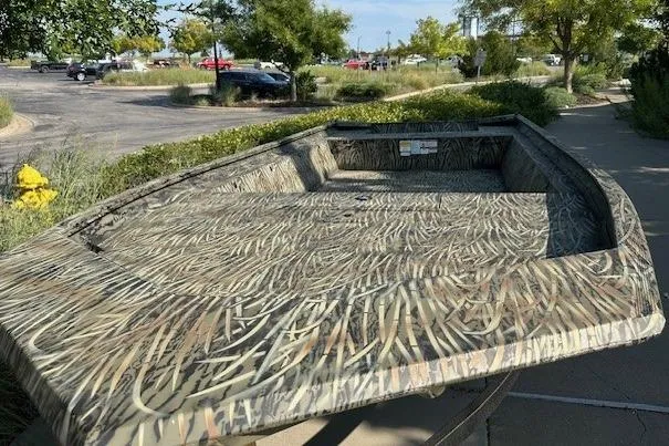 Slide: The Image of 2025 Tracker GRIZZLY 1860 Utility boat with camouflage design in a parking lot. - 2