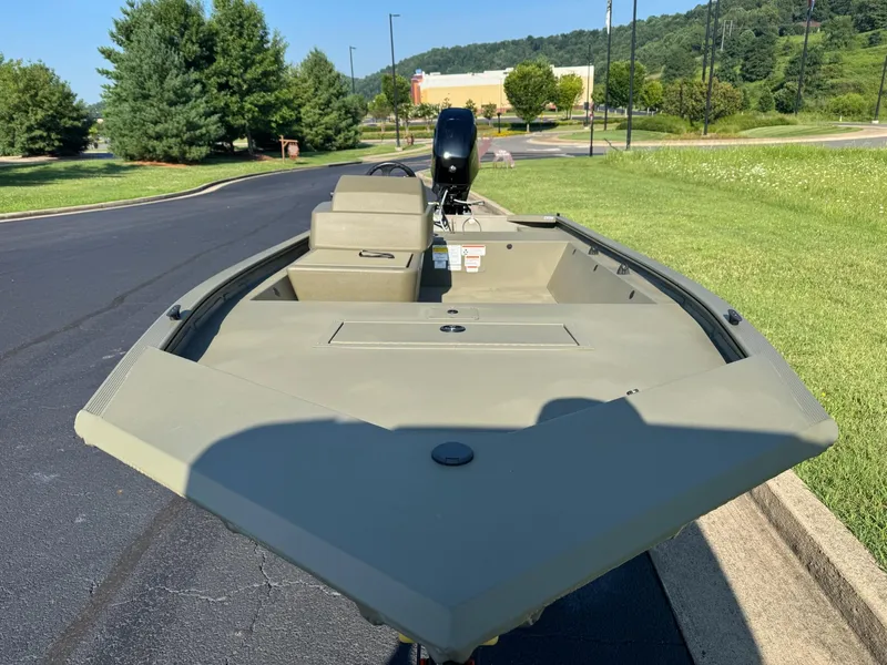 Slide: The Image of 2025 Tracker Grizzly 1648 SC boat on pavement, surrounded by greenery and trees. - 4