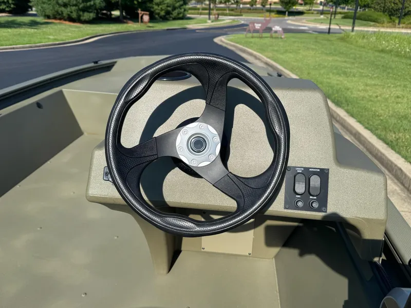 Slide: The Image of 2025 Tracker Grizzly 1648 SC boat steering wheel and control panel in sunlight. - 6