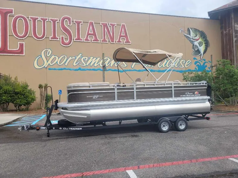 The Image of 2025 Sun Tracker SportFish 22 DLX pontoon boat on trailer, parked outdoors. - 0