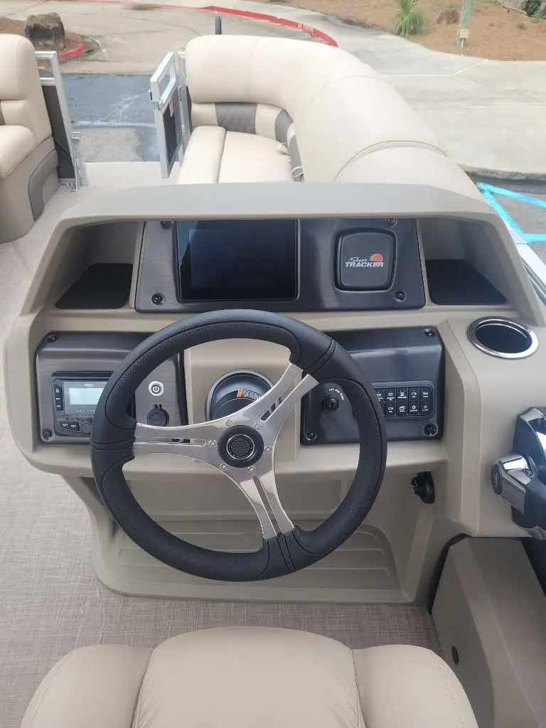 Slide: The Image of 2025 Sun Tracker SportFish 22 DLX interior with beige seating and outdoor view. - 8
