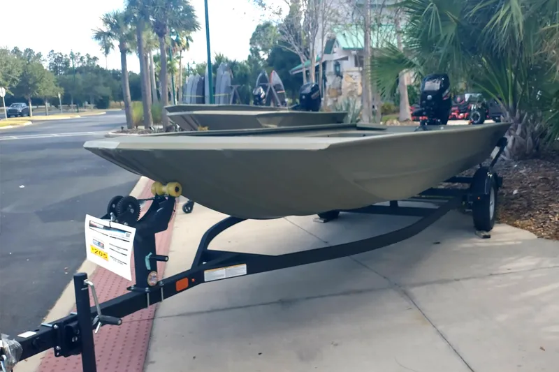 The Image of 2025 Tracker Grizzly 1860 Utility boat on trailer, parked outdoors near palm trees. - 0