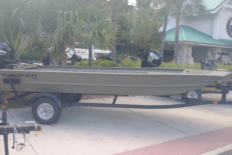 Slide: The Image of 2025 Tracker Grizzly 1860 Utility boat on trailer, parked outdoors near palm trees. - 3