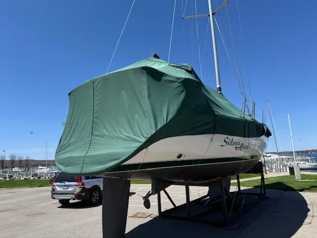 Slide: The Image of 2001 Beneteau 411 sailboat covered in green tarp, parked on a stand in a marina. - 15