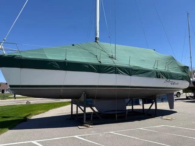 Slide: The Image of 2001 Beneteau 411 sailboat covered with green tarp on a stand in a parking lot. - 2