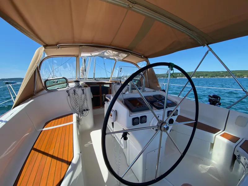 Slide: The Image of 2001 Beneteau 411 sailboat cockpit with steering wheel, wooden seating, and ocean view. - 3