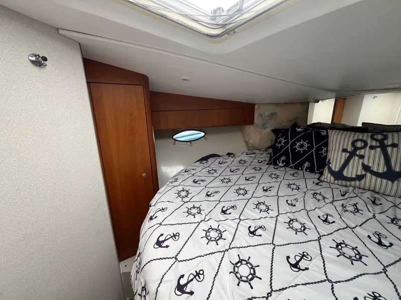 Slide: The Image of 1996 Silverton 362 Sedan Cruiser cabin with nautical-themed bedding and wooden cabinetry. - 39