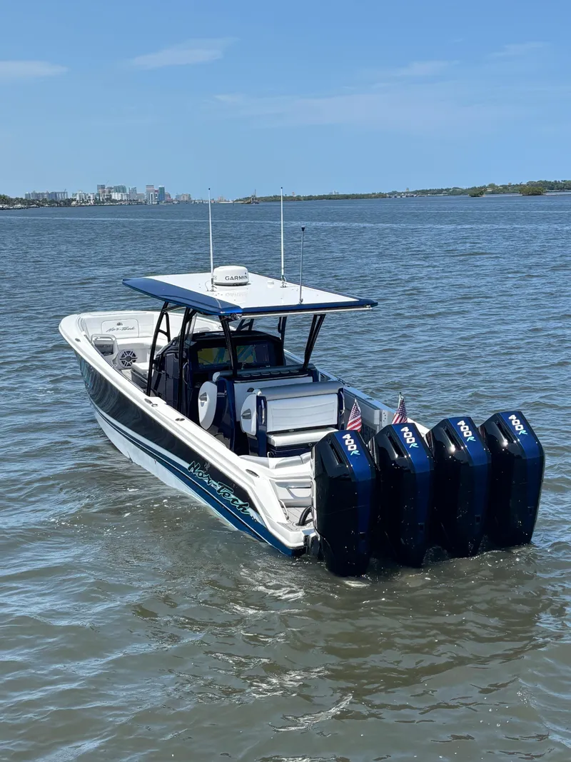 Slide: The Image of 2024 Nor-Tech 390 Sport Center Console boat with four engines on open water. - 4