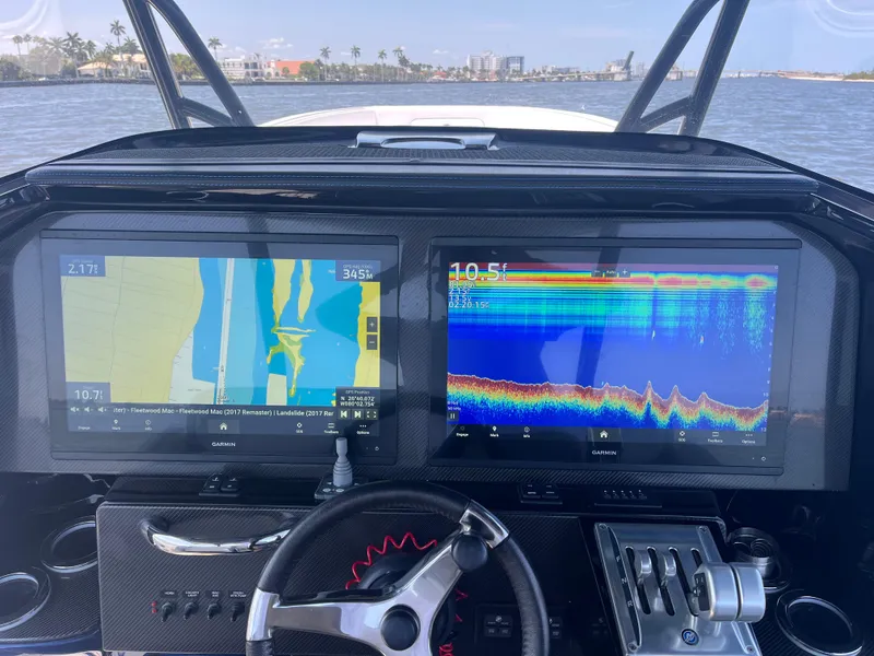 Slide: The Image of 2024 Nor-Tech 390 Sport Center Console dashboard with dual navigation screens on open water. - 9