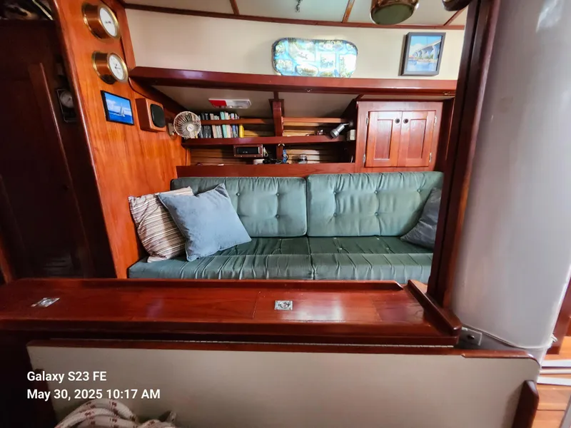 Slide: The Image of Interior of a 1989 Valiant 40 Cutter sailboat with green sofa and wooden cabinetry. - 13