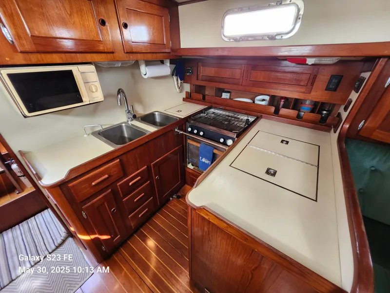Slide: The Image of 1989 Valiant 40 Cutter kitchen with wood cabinetry, dual sinks, stove, and microwave. - 15