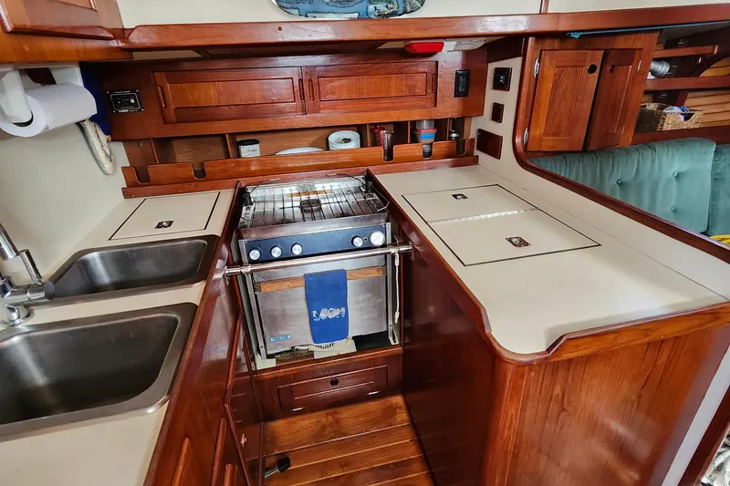 Slide: The Image of 1989 Valiant 40 Cutter yacht kitchen with wooden cabinetry, dual sinks, and stove. - 16