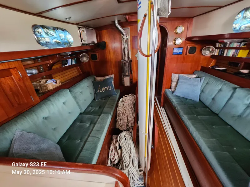 Slide: The Image of 1989 Valiant 40 Cutter interior with teal seating, wood paneling, and nautical decor. - 8