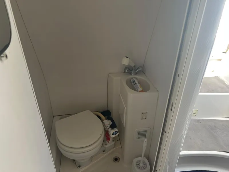Slide: The Image of Compact bathroom in a 1997 Chris-Craft 26 Crowne Cruiser boat, featuring a toilet and sink. - 13