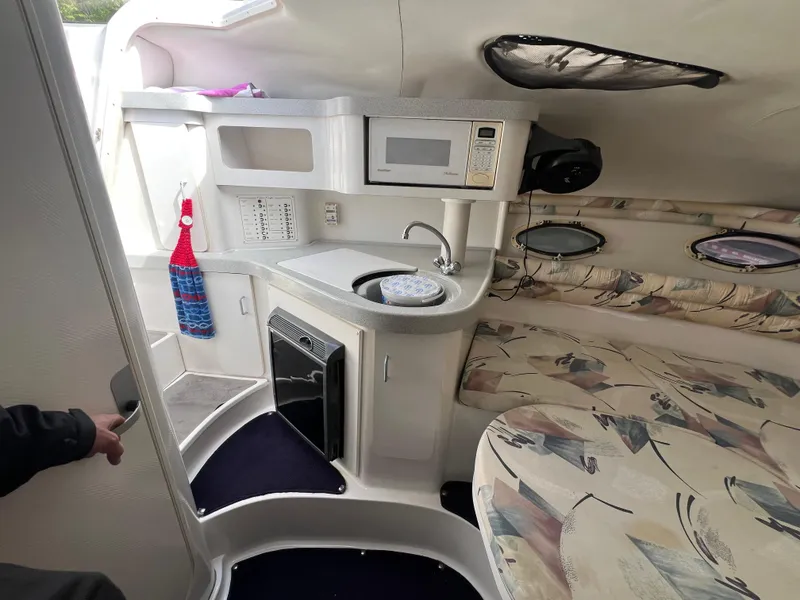 Slide: The Image of 1997 Chris-Craft 26 Crowne Cruiser interior with kitchenette and seating area. - 14