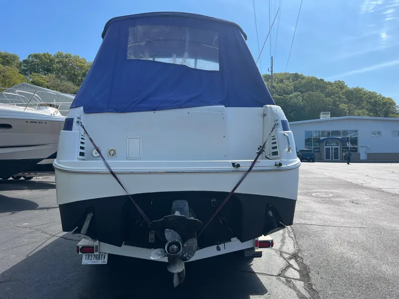 Slide: The Image of 1997 Chris-Craft 26 Crowne Cruiser boat with blue cover, parked outdoors. - 3