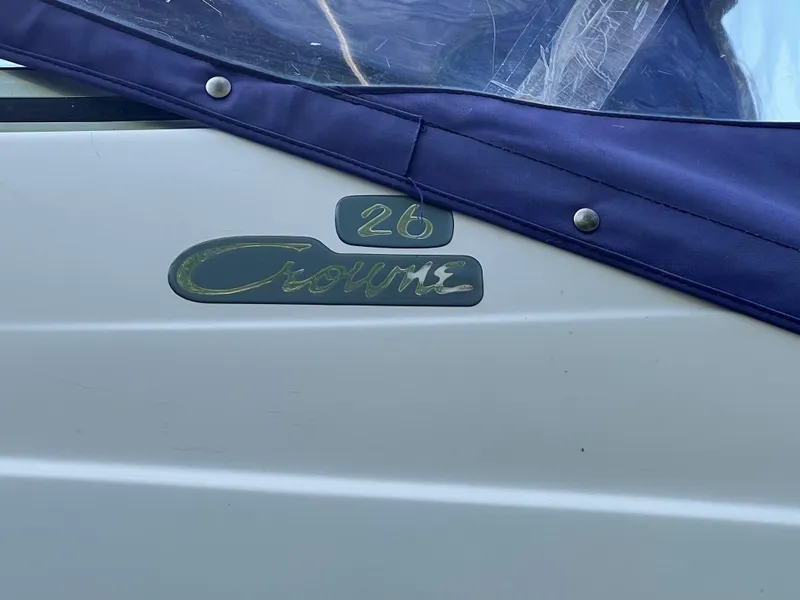 Slide: The Image of 1997 Chris-Craft 26 Crowne Cruiser boat with blue cover and logo detail. - 5