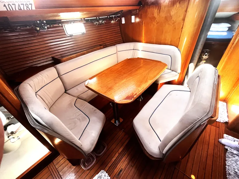 Slide: The Image of Cozy interior of 1990 Jeanneau Sun Magic 44 sailboat with wooden table and cushioned seating. - 2