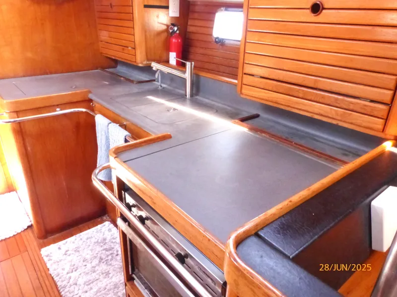 Slide: The Image of Galley kitchen in 1990 Jeanneau Sun Magic 44 sailboat with wood cabinetry and stainless steel fixtures. - 3