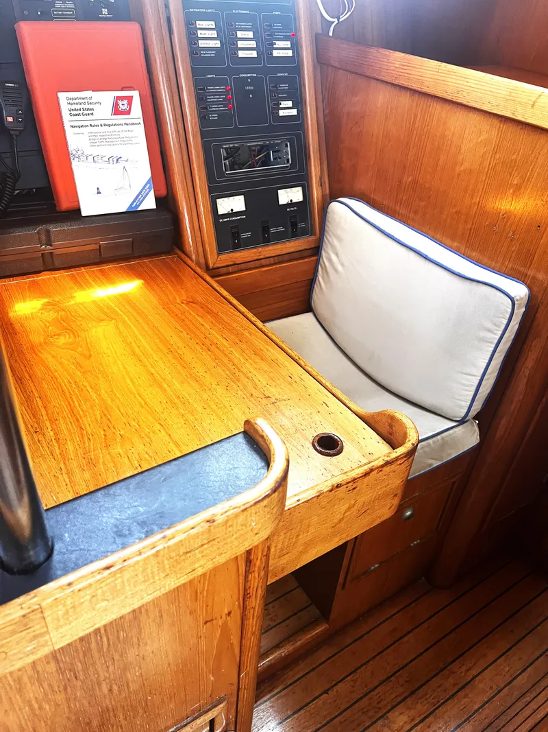 Slide: The Image of Navigation station on 1990 Jeanneau Sun Magic 44 yacht with wooden desk and cushioned seat. - 7