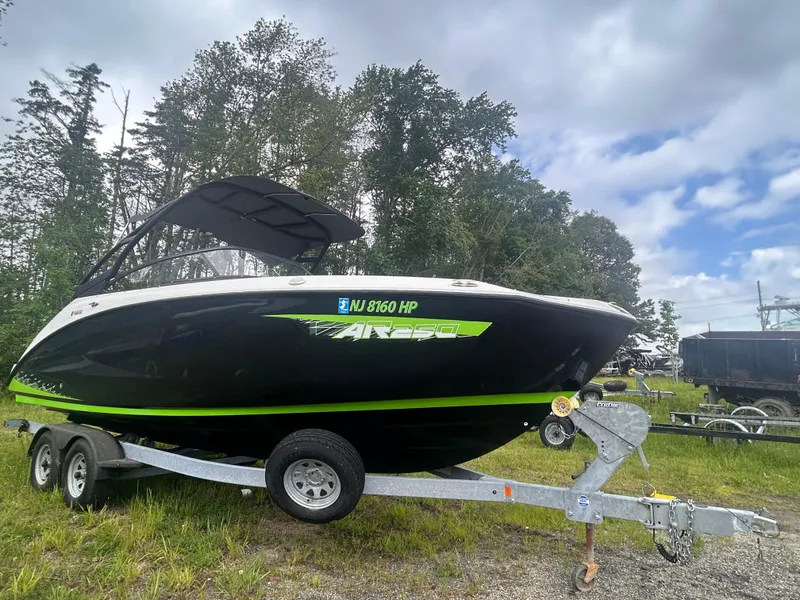 The Image of 2021 Yamaha Boats AR250 on trailer, parked outdoors with trees and cloudy sky in background. - 1