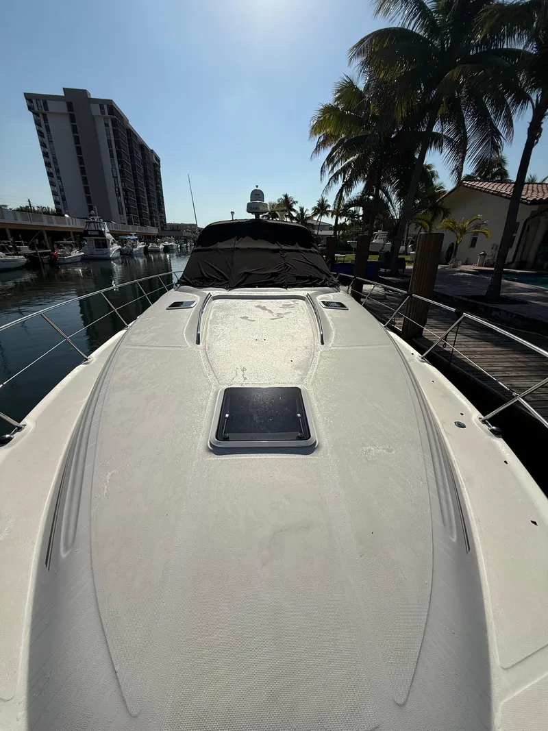 Slide: The Image of 2002 Sea Ray 410 Sundancer yacht docked near palm trees and waterfront buildings. - 2