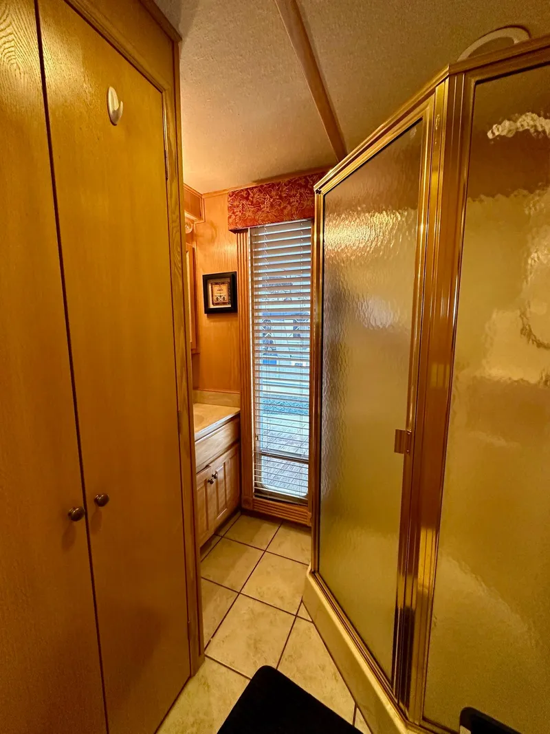 Slide: The Image of Compact bathroom in 2004 Lakeview 16x68 houseboat with shower and wooden cabinetry. - 12