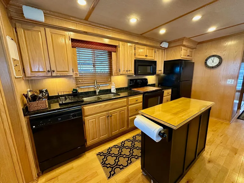 Slide: The Image of Modern kitchen in 2004 Lakeview 16x68 houseboat with wooden cabinets and black appliances. - 4